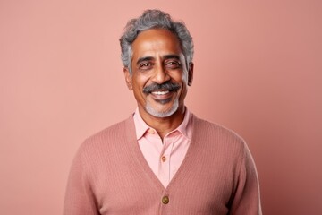 Obraz premium Portrait of Indian senior man smiling and looking at camera against pink background