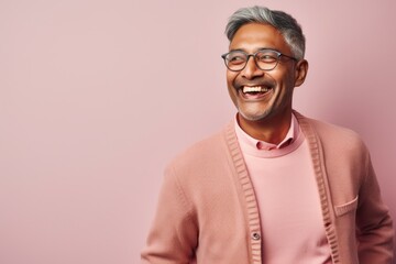 Obraz premium Portrait of a cheerful Indian asian man wearing eyeglasses standing against pink background
