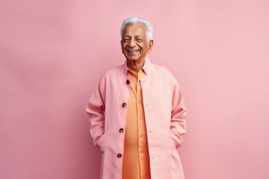 Portrait of a happy senior asian man in pink coat standing against pink background