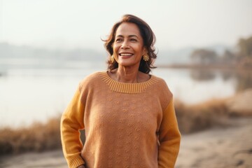 Portrait of a smiling woman in sweater standing on the beach and looking at camera