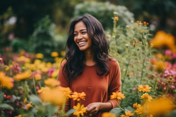 Naklejka premium Beautiful african american woman smiling and looking at camera in flower garden