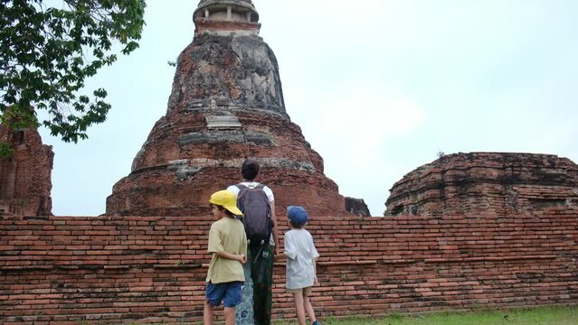 Buddhist temple complex in ayutthaya, father guiding young sons through historic unesco world heritage landscape, reflecting traditional thai cultural heritage