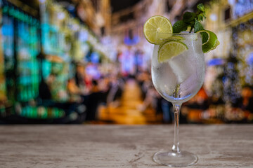 Close-up Of A Cocktail Or Mojito In A Bar. People Blurred In The Background. Selective Focus On The Iced Drink And The Glass.