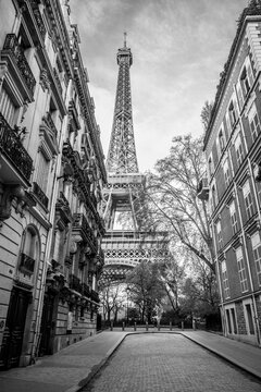 View of the Eiffel Tower from a nearby street full of residential buildings. Paris, France. Black and white photography.