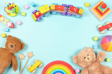 Baby kids toy frame background. Teddy bears, colorful wooden educational, sensory, sorting and stacking toys for children on light blue background. Top view, flat lay