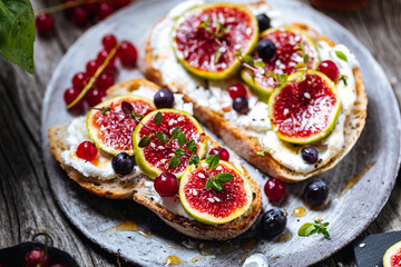 Toast spread with cream cheese, figs, currants and honey. Tasty and healthy brunch. Colourful scene.