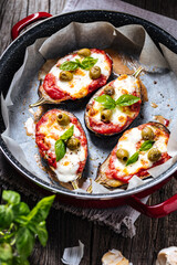 Healthy pizza with eggplant or aubergine with tomato sauce, mozzarella cheese and basil leaves. Placed on rustic wooden board with ingredients