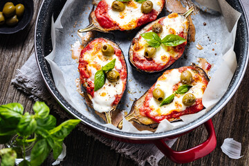 Healthy pizza with eggplant or aubergine with tomato sauce, mozzarella cheese and basil leaves. Placed on rustic wooden board with ingredients