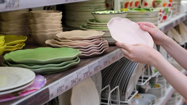 Young woman chooses plate close-up. Buying tableware