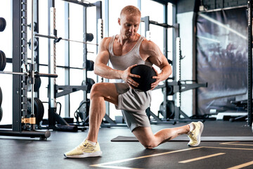 Fototapeta na wymiar Fit and muscular man exercising with medicine ball at gym.