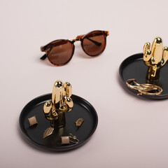 Holder with a set of luxurious jewelry on white background, space for text. Minimal fashion composition with golden elements. Golden cactus