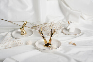 Holder with a set of luxurious jewelry on white background, space for text. Minimal fashion composition with golden elements. Golden horns, golden rabbit 