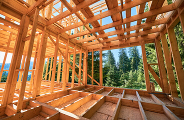 Under-construction residential wooden frame home located near a forest. Commencement of a new...