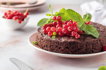 Tasty homemade chocolate cake brownie decorated with red currant berries and mint on white marble table close up