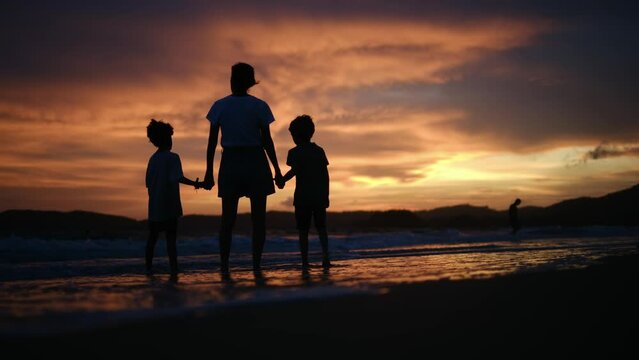 happy family. mother and kids by the sea at sunset silhouette. mother and child kids reach out to the sun. kid dream concept. happy family little kids and dad alone with nature relax sunset concept