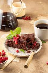 Two pieces of chocolate cake brownie decorated with red currant berries and mint for coffee on beige textured background