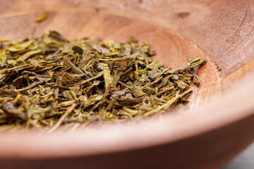 Sencha japanese dried green tea leaves in a wooden dish