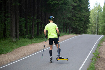 A man on a roller ski rides in the park.Cross country skilling.