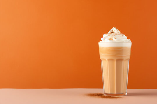 Seasonal pumpkin spice latte on orange background.