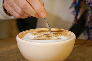 Close up view of a person mixing a cup of coffee.