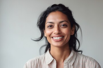 Close-up portrait of an Indian woman in her 30s in a minimalist background