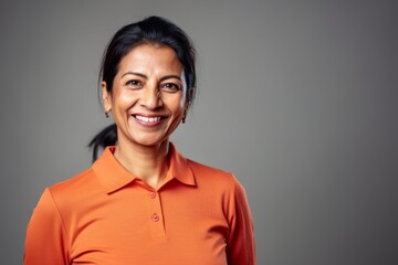 Lifestyle portrait of an Indian woman in her 40s wearing a sporty polo shirt in a minimalist background