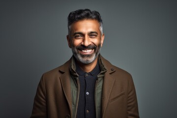 Fototapeta premium Lifestyle portrait of an Indian man in his 40s in a minimalist background