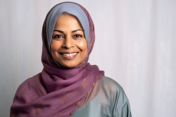Lifestyle portrait of an Indian woman in her 50s wearing hijab in a minimalist background