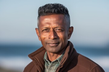 Portrait of mature man smiling at camera on beach during autumn day