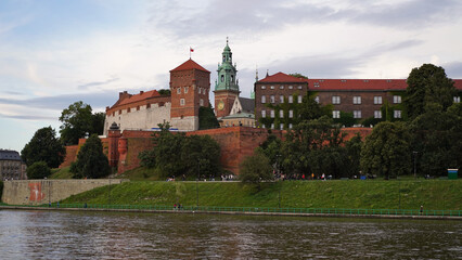 Fototapeta na wymiar Beautiful old royal Wawel Castle on the banks of Vistula river in the evening. The main historical landmark of Krakow, a popular tourist destination in Poland.Old town, place for vacation and travel.