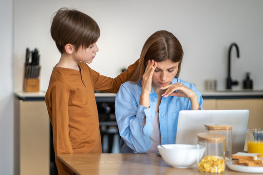 Teenage boy calms down mother. Empathetic sympathetic child strokes frustrated sad tired stressful mom on head, helping to cope with tension. Emotionally close family, warm relationships.