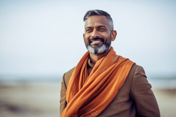 Portrait of a handsome Indian man with orange scarf on the beach
