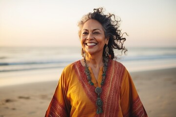 Portrait of happy senior woman smiling at camera on beach during sunset