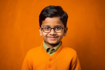 Cute indian little boy wearing eyeglasses on orange background