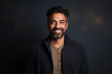 Fototapeta premium Portrait of a handsome Indian man smiling at the camera on black background
