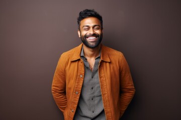 Obraz premium Portrait of a happy young indian man smiling against brown background
