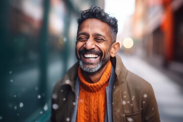 Fototapeta premium Portrait of a smiling Indian man walking in the street with snow falling