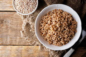 Barley porridge in a bowl on a wood background