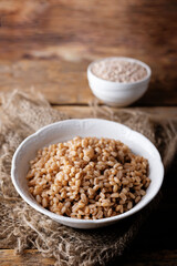 Barley porridge in a bowl on a wood background