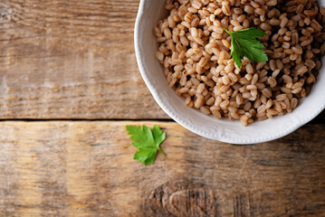 Barley porridge in a bowl on a wood background