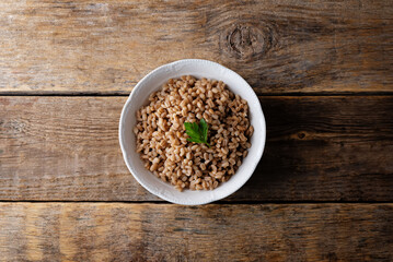 Barley porridge in a bowl on a wood background