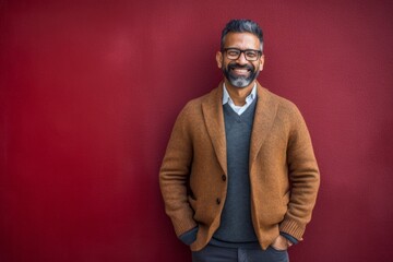 Portrait of smiling Indian man with eyeglasses against red background
