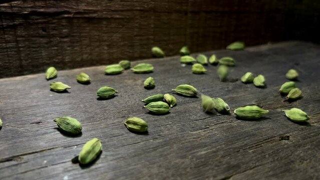 Close footage of cardamom spices on wooden board with yellow light   on two side,