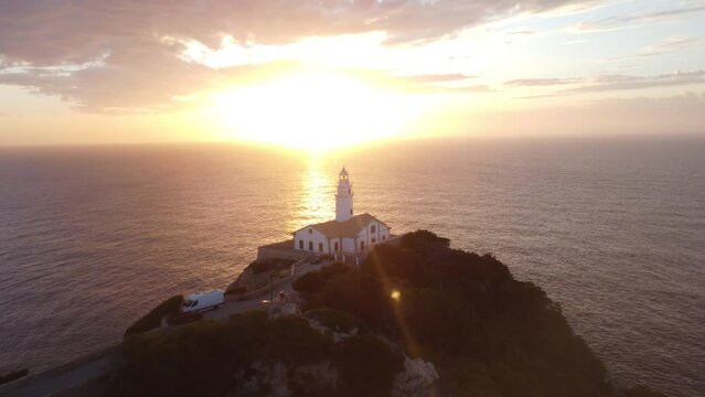 Drone footage over Far de Capdepera lighthouse in Spain with golden sunset sky