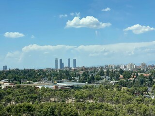 Aerial view of a lush green park surrounded by trees, with a city skyline in the background