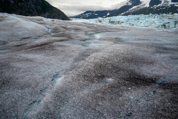 a large patch of snow on a mountain slope next to trees and mountains