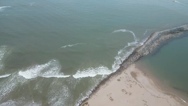 Drone footage over sandy beach by large splashing foamwaves