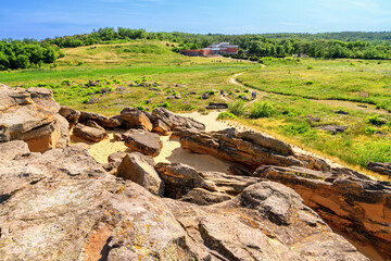 Summer landscape - view of the ancient mound of sandstone boulders and the building of the museum...