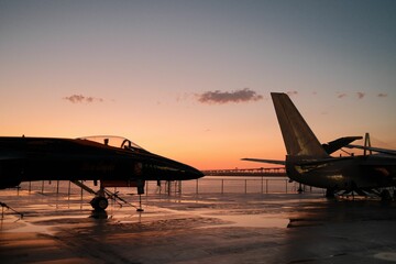 two jets sitting on a tarmac next to the ocean - obrazy, fototapety, plakaty