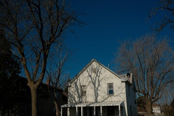 White house with a large tree providing shade in the foreground